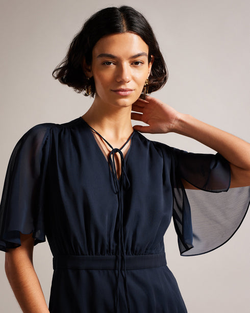 GIGGIE-Dresses-Add a touch of retro style to your wardrobe with GIGGIE. This dress features a fit and flare silhouette, with sheer fluted sleeves and a ruffle tiered skirt that are sure to make you stand out at your next event.The shell of this product is made of 100% recycled polyester. Using recycled polyester helps divert plastic waste from ending in landfills and helps us to reduce our dependency on virgin materials. Mini dress Tiered skirt with ruffles Fit and flare Sheer fluted sleeves Neck tie V neck